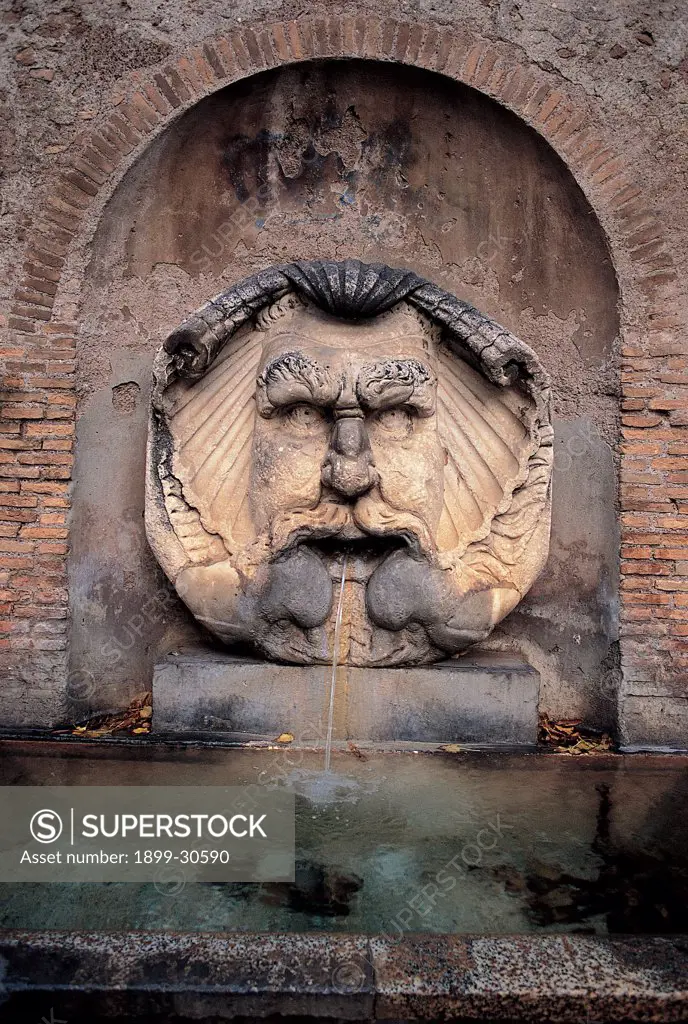 Fountain Mascherone of Santa Sabina, by Munoz (Munoz) Antonio, 1936, 20th Century, Unknow. Italy, Lazio, Rome, Piazza Pietro d'Illiria. Detail Mascherone fountain face valve jet shell niche water.