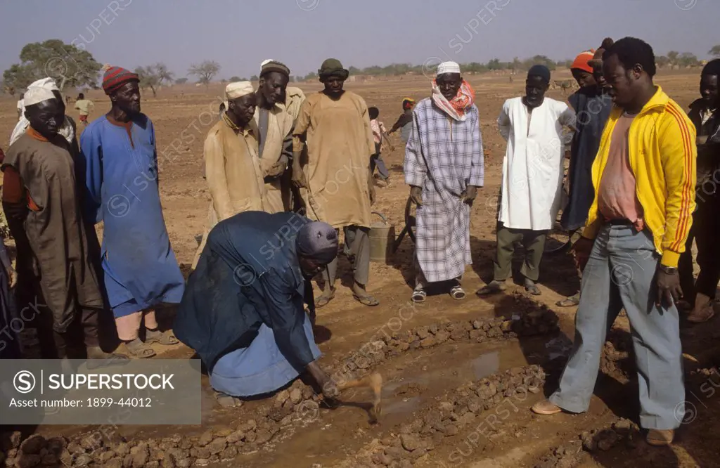 EROSION CONTROL, BURKINA FASO. Yatenga Province,Kalsaka village. Building stone lines to prevent erosion. - demonstration showing the effectiveness of stone lines to control erosion. . Stone lines have been built along level contours and the ground doused with water. This time the water stays. 