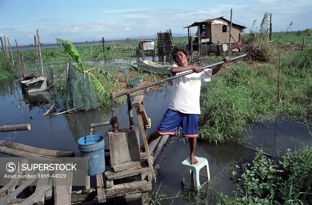 WATER AND SANITATION, PHILIPPINES. Cebu City. Woman collecting water from a submerged standpipe. . These families are too poor to buy homes inland with access to clean water. They are forced to build make shifthouses along estuaries which are flooded for six to eight months a year. There is no sanitation system and rubbish is dumped in the water. Many people in the community are affected by disease. 