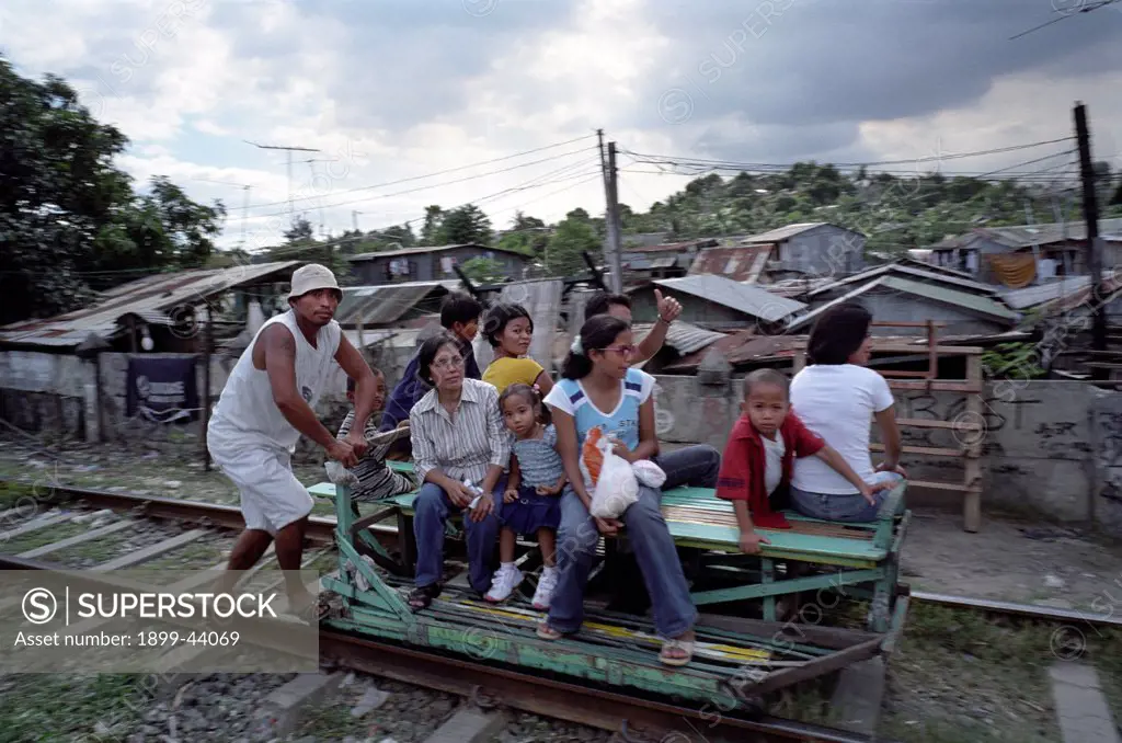 PHILIPPINES. Manila. Sucat Railway Community. Human powered railway taxi. . Young men ferry passengers along the tract in makeshift wagons. When trains come they lift the wagons off the track, wait until the coast is clear and resume their journey. Over 10,000 families live along this railway track. There are plans to upgrade the line which would mean the community would have to re-locate. 