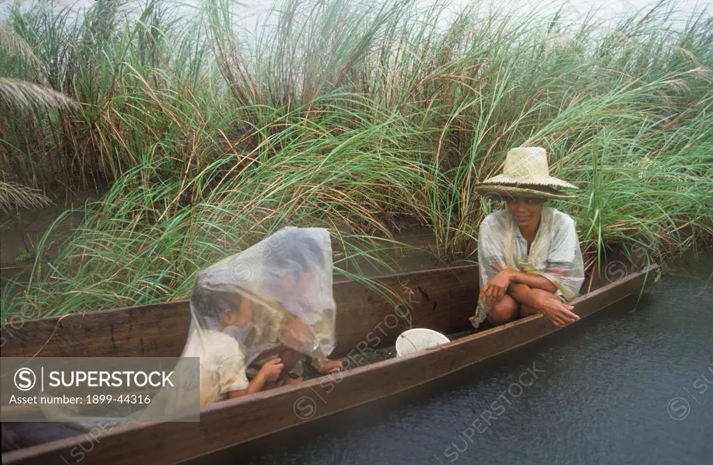 WEATHER, PHILIPPINES. A family shelters from torrential monsoon rain in a small boat. . 
