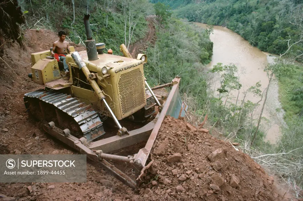 AMAZON - PERU. Satipo - Puerto Prado Road. . A bulldozer scraping the bed of an east-west running road connecting Satipo to Puerto Prado on the humid, eastern side of the Peruvian Andes east of Lima. Roads, whether for transport or logging, serve to open up the rainforest to settlers. 