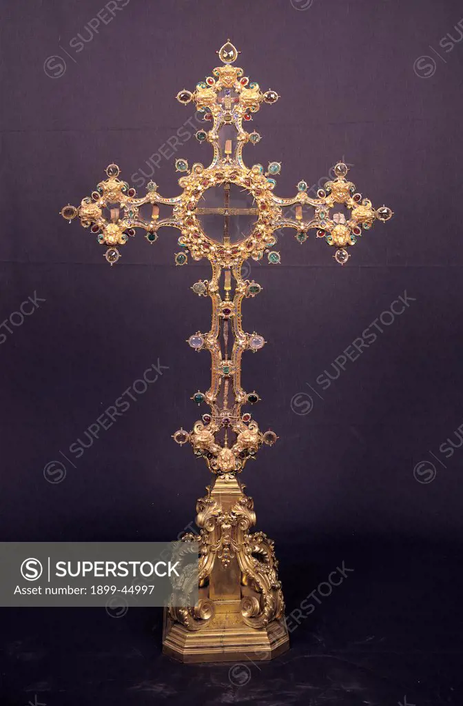 Reliquary Cross, by Holzmann Bernardo, Merlini Cosimo II (The Younger), 1618, 17th Century, embossed and chased gold, enamels, miscellaneous gems. Italy: Tuscany: Florence: Opera di Santa Maria del Fiore Museum. Whole artwork. Reliquary cross gold embossed pedestal fragment cross Jesus Christ wood thorn piece dress/clothes gems decoration enamels precious stones