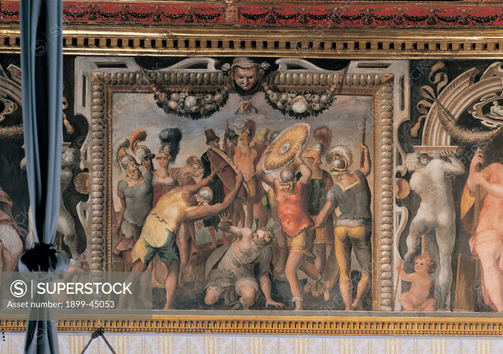 The Punishment of Tarpeia, by follower Mazzoni Giulio, 1550, 16th Century, fresco. Italy: Lazio: Rome: Palazzo Spada: Stanza con storie dell'antica Roma. Whole artwork. Girl woman Tarpeia traitress/betrayer Roman soldiers fellow citizens killing murder shields cuirasses helmet feathers/plumes red yellow painted frame garlands festoons flowers fruits