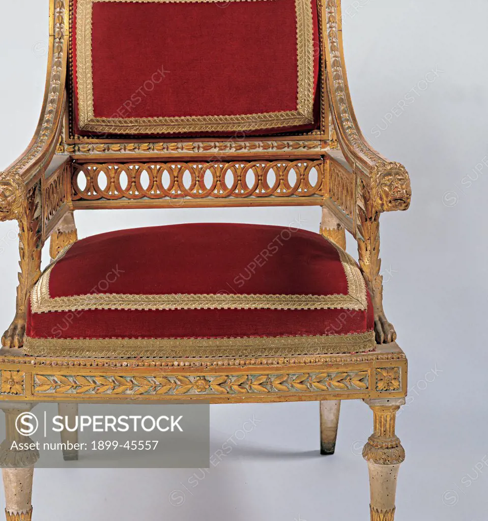 Armchair, by Lombard workmanship, 1780, wood carved, gilded and partially painted, padded seat and back covered with fabric. Italy: Lombardy: Mantua: Ducal Palace. Detail. Chair armchair seat upholstery decoration furniture furnishings fittings design backrest sunken armrests gold red leonine lion's heads
