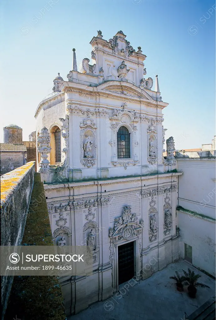 Convent of Santa Maria del Carmine, Lecce, by Manieri Mauro, Cino Giuseppe, 1711, 18th Century, Lecce stone. Italy: Puglia: Lecce: Lecce: Santa Maria del Carmine Convent. Aall. Exterior church Monastery of Santa Maria del Carmine foreshortened view facade superimposed orders Lower order doorway carved piers pediment carved mixtilinear tympanum/gable crest/coat of arms Corinthian grooved pilaster-strips base plinth niches with arabesques statues prophets saints garlands cornice string-course dent