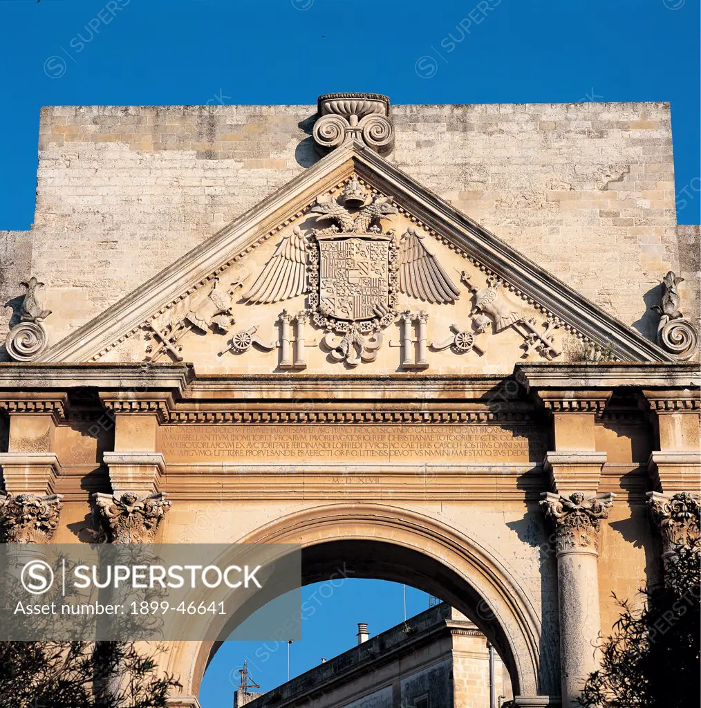 Triumphal Arch of Charles V, Lecce (Porta Napoli), by Dell'Acaya (o Acaja) Gian Giacomo, 1548, 16th Century, Lecce stone. Italy: Puglia: Lecce: Lecce: Triumphal Arch of Charles V: Porta Napoli. Detail. Town gate Charles V Triumphal Arch Porta Napoli Naples Gate arch round arch Corinthian-style paired columns smooth shaft/trunk triangular pediment carved tympanum/gable heraldic crest/coat of arms two-headed eagle Habsburg family Imperial crest/coat of arms commemorative inscriptions cornice denti