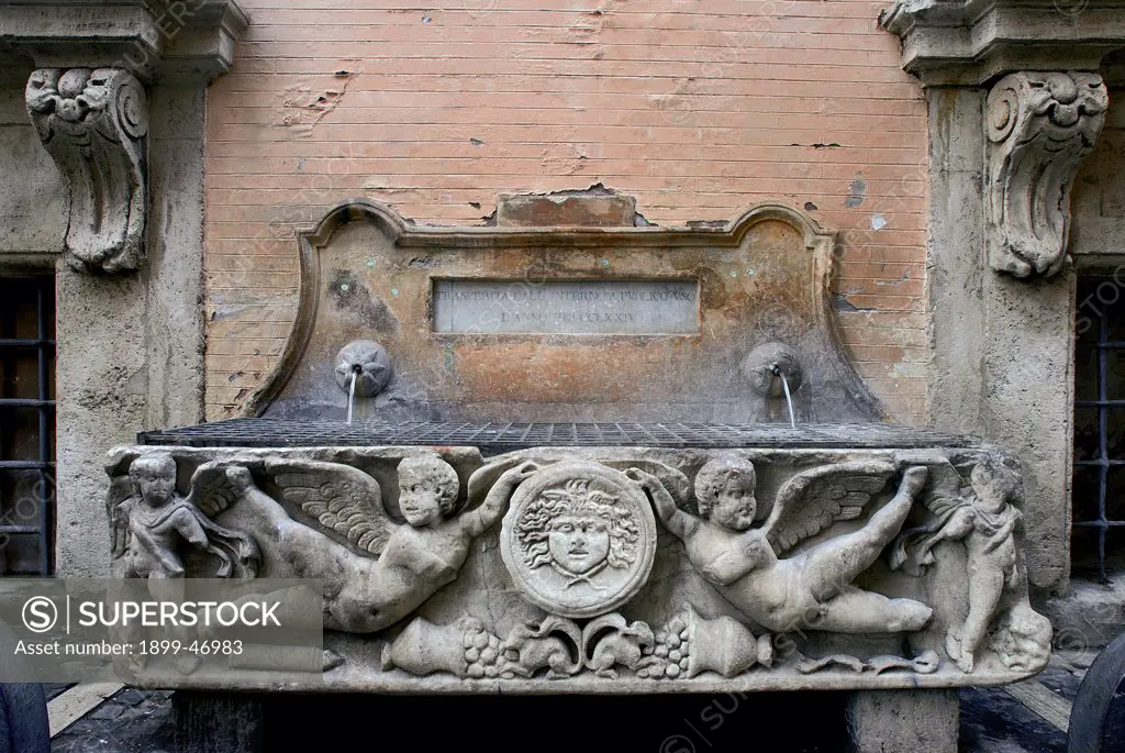 Fountain in Via Santo Stefano del Cacco, by Unknown artist, 17th Century, . Italy: Lazio: Rome: Via Santo Stefano del Cacco. View fountain winged putti Medusa basin sarcophagus inscription
