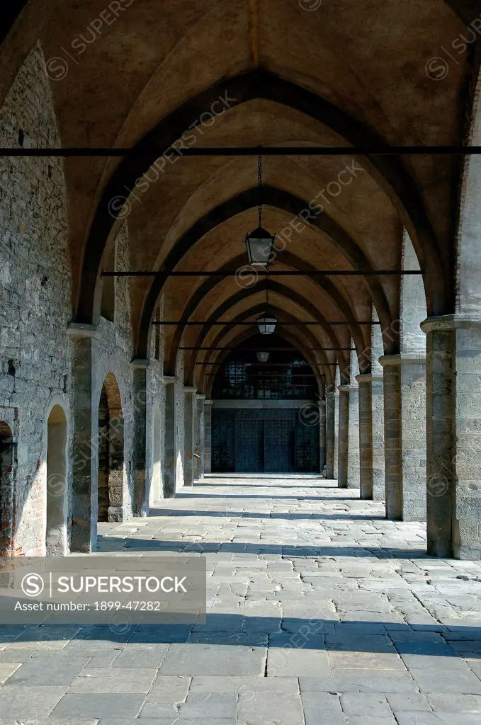 Portico in Piazza Cittadella - Bergamo, by Unknown artist, 1355, 14th Century, . Italy: Lombardy: Bergamo: Piazza Cittadella. View portico/porch pointed arch/ogive floor cross vault stone brick pillars doors lamps chains
