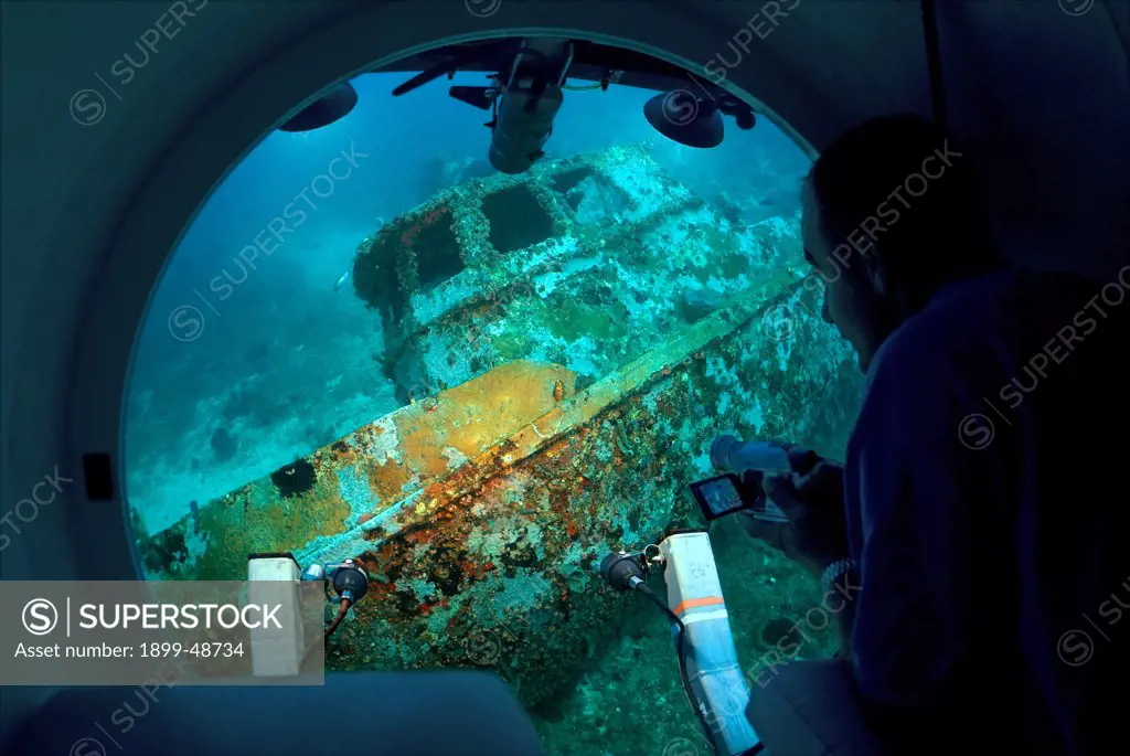 Man looking out of mini-sub window at an wreck dive site. At approximately 150 feet. Sea Aquarium Reef, Curacao, Netherlands Antilles. . . Model and Property Release: Yes