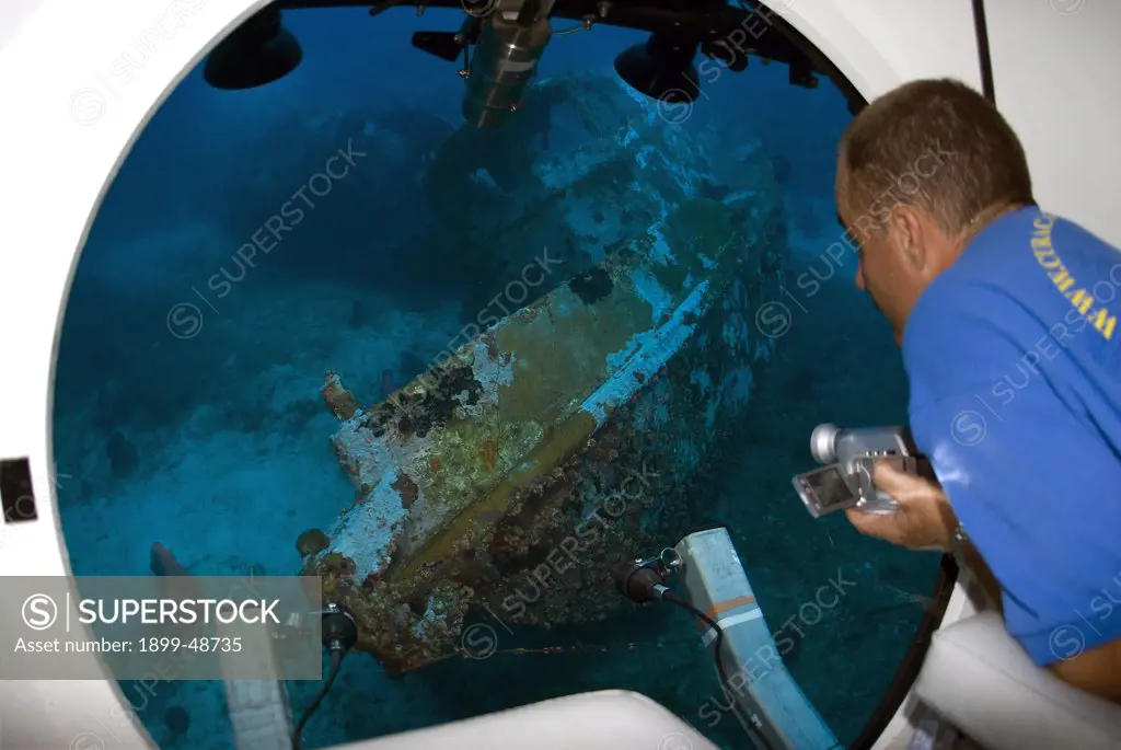 Man looking out of mini-sub window at an wreck dive site. At approximately 150 feet. Sea Aquarium Reef, Curacao, Netherlands Antilles. . . Model and Property Release: yes