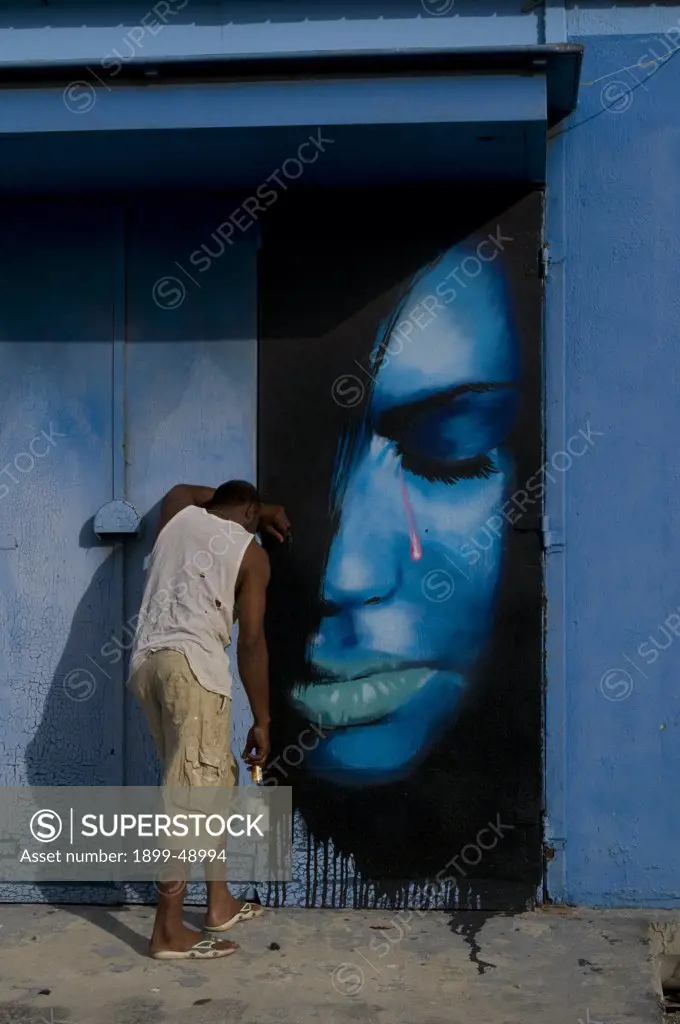 Drunken homeless man in front of a mural painted on exterior wall of a bar in Curacao, Netherlands Antilles.