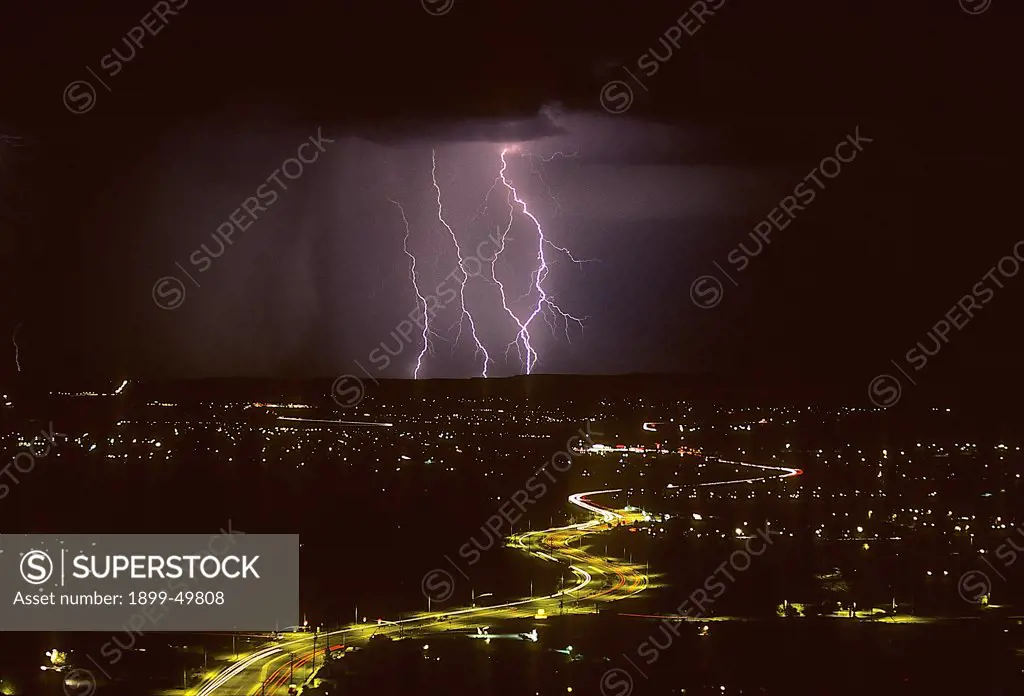 Cloud-to-ground lightning with city lights.   Tucson, Arizona, USA.