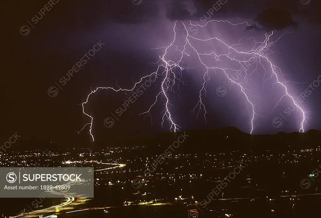 Dramatic, intricately branched cloud-to-ground lightning with air discharge channels and five contact points, plus city lights.  Tucson, Arizona, USA.