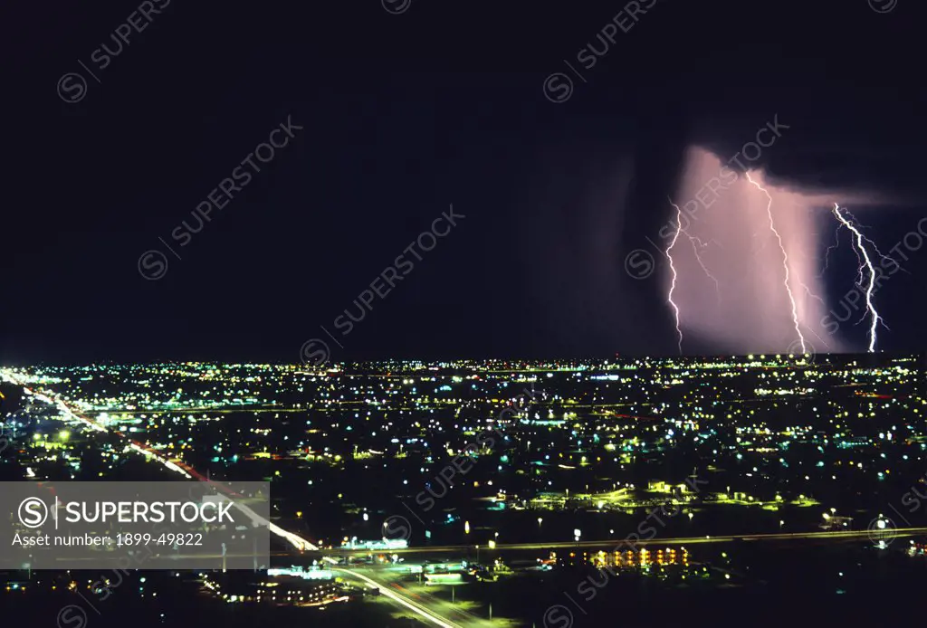 Storm front with lightning on the horizon over city.  Tucson, Arizona, USA.