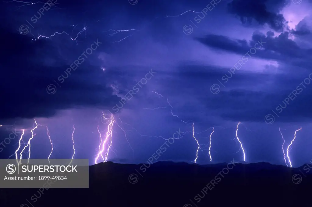 Three-minute exposure of an electrical storm, showing multiple cloud-to-ground lightning strikes, accompanied by air discharge lightning and intracloud lightning among the clouds.  Roskruge Mountains, southern Arizona, USA.