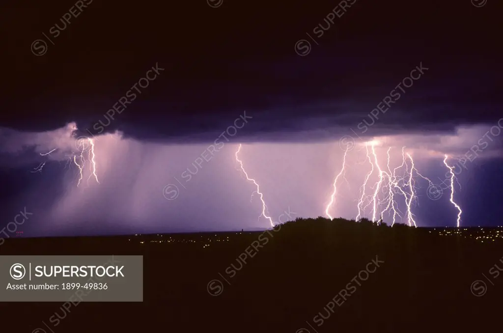 Summer monsoon storm with lightning, a series of cloud-to-ground discharges illuminating a curtain of rain.  Tucson, Arizona, USA.