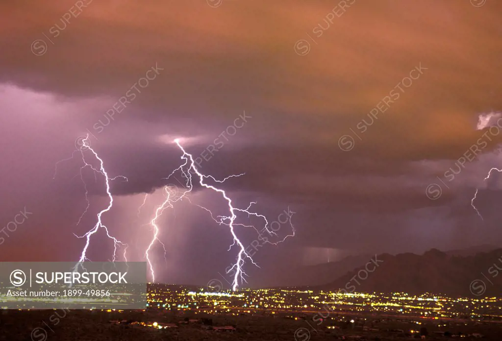 Sunset storm as seen from the Tucson Mountains looking northwest, with multiple cloud-to-ground lightning strikes in the city due west of the Santa Catalina Mountains.  Tucson, Arizona, USA.