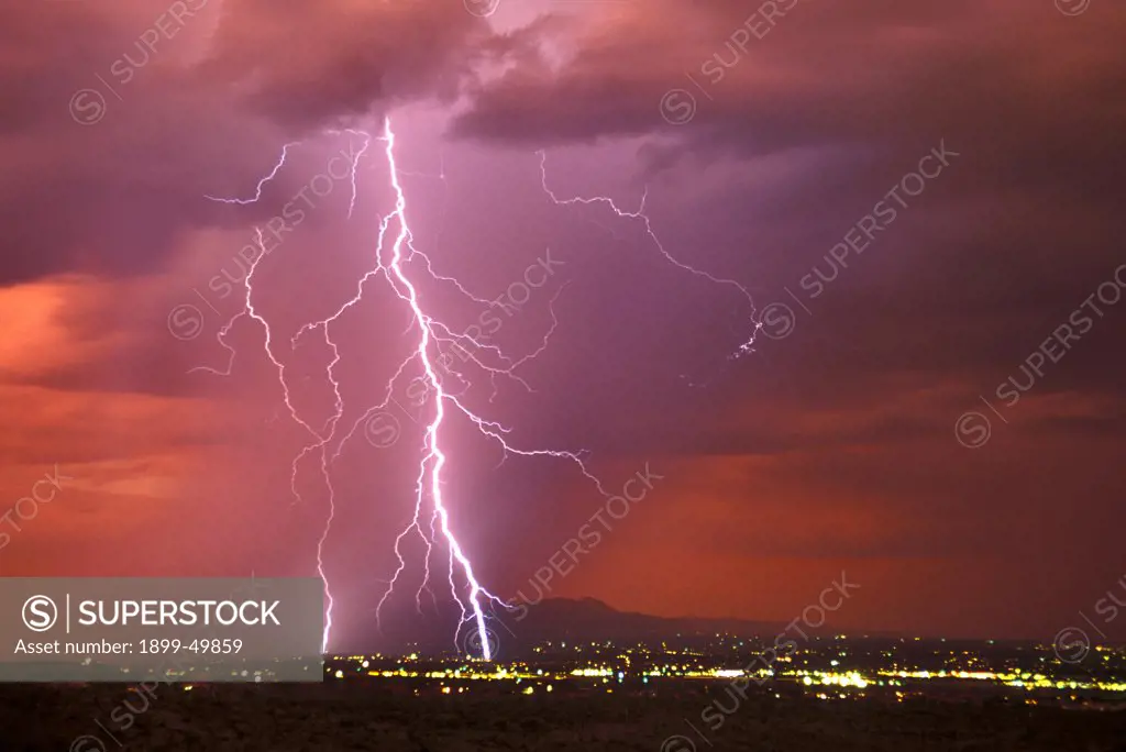 Sunset rainstorm as seen from the Tucson Mountains looking north, with two cloud-to-ground lightning strikes, one within a rain shaft.  Tucson, Arizona, USA.