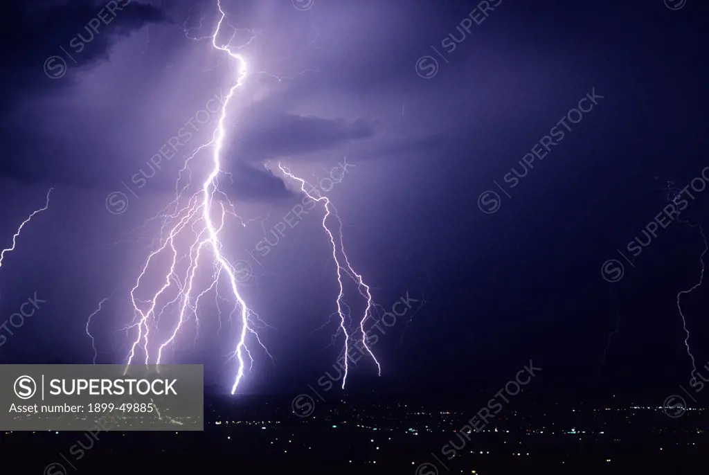 Powerful cloud-to-ground lightning strikes over the foothills of the Tucson Mountains.  Tucson, Arizona, USA.