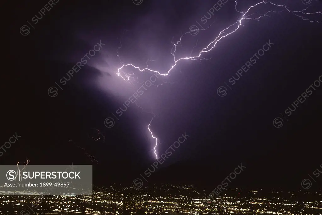 Spectacular example of air discharge lightning, a lightning crawler, over city with one prominent cloud-to-ground strike in the Santa Catalina Mountains.  Tucson, Arizona, USA.