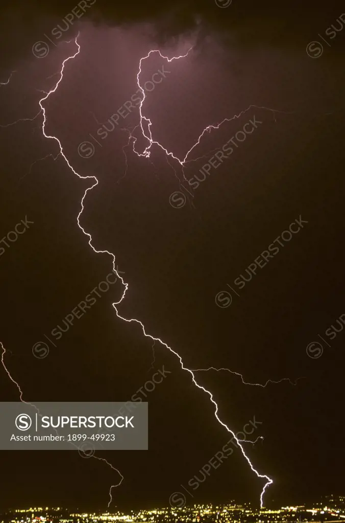 Zigzag cloud-to-ground lightning strike with air discharge lightning over city at night.  Tucson, Arizona, USA.