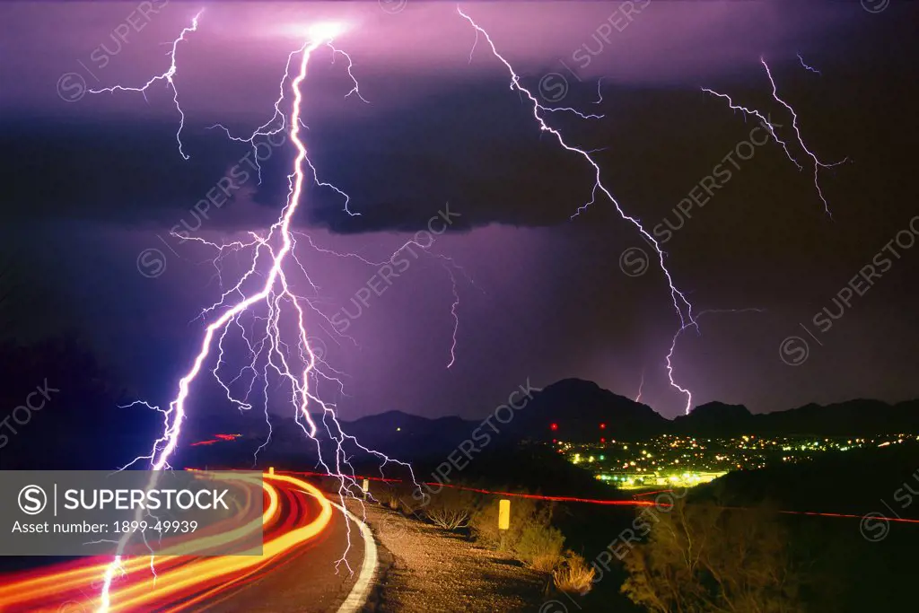 Sonoran Desert rainstorm, a summer monsoon thunderstorm with cloud-to-ground lightning strikes and light trails from cars on roadway. This image was created from two film originals, scanned and digitally combined in Photoshop. Tucson Mountains, Tucson, Arizona, USA. Multiple Exposure