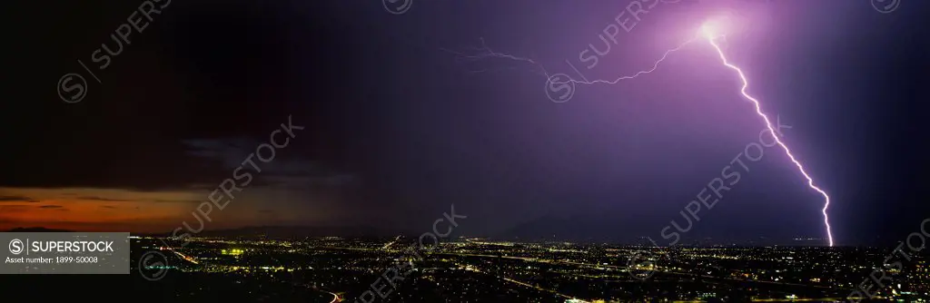 Powerful streak lightning, a cloud-to-ground discharge over city.  Tucson, Arizona, USA. Panoramic 6x17 film