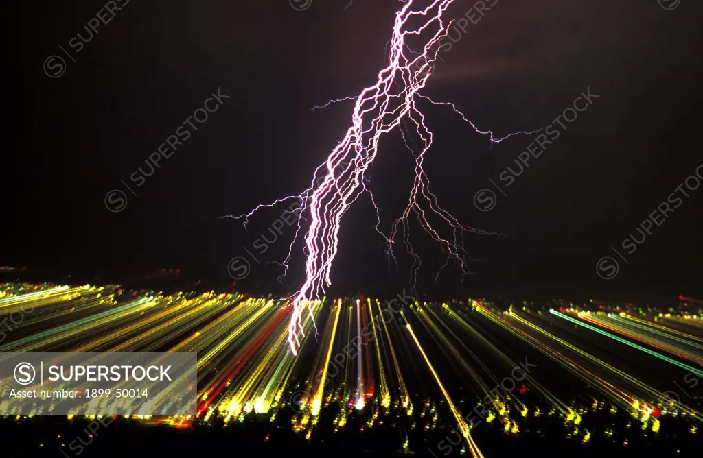 View of separated lightning strokes in a cloud-to-ground lightning strike over city at night. This picture of scientific interest was made possible by zooming a photographic lens during the full interval of the lightning flash, thereby separating and recording on film each electrical stroke contained within the strike. And the effect of zooming records the city lights as streaks across the film. Tucson, Arizona, USA.