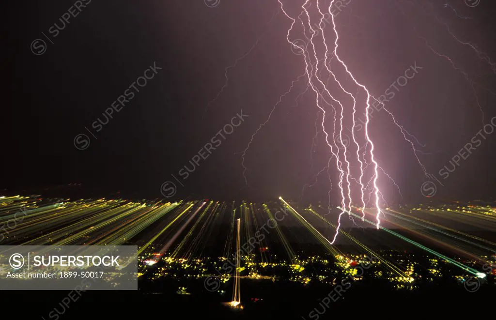 View of separated lightning strokes in a cloud-to-ground lightning strike over city at night.  This picture of scientific interest was made possible by zooming a photographic lens during the full interval of the lightning flash, thereby separating and recording on film each electrical stroke contained within the strike.  And the effect of zooming records the city lights as streaks across the film. Tucson, Arizona, USA.