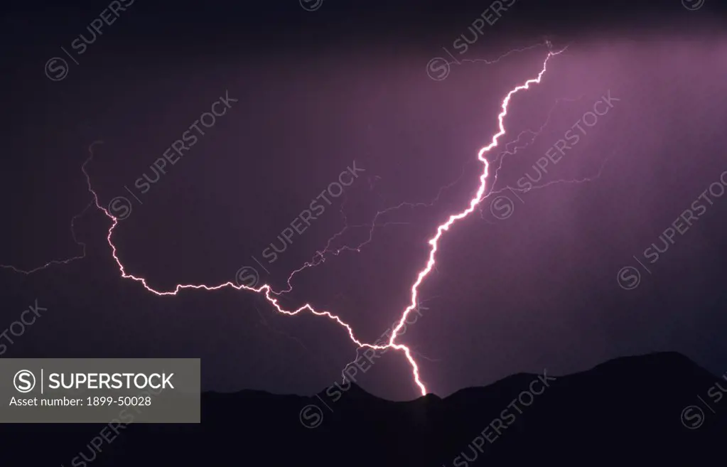 Unusual example of forked ground-to-cloud lightning with what appears to be two primary channels joining into one near the ground.   Tucson Mountains, Tucson, Arizona, USA.