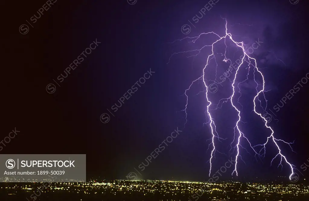 Forked cloud-to-ground lightning discharge with four strike points on the horizon.  Tucson, Arizona, USA.