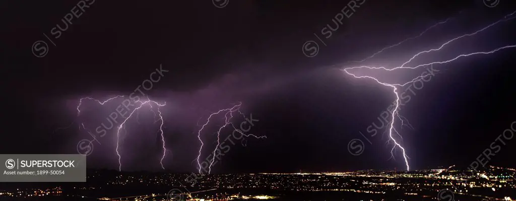 On right, two types of lightning from one forked channel, cloud-to-air and cloud-to-ground discharges.  Summer monsoon season. Tucson, Arizona, USA.  Panoramic 6x17 film