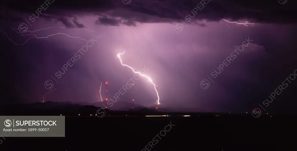 Lightning storm in northwest Tucson near Interstate 10, with three illuminated broadcasting towers. Powerful cloud-to-ground strike accompanied by air discharges. Summer monsoon season. Tucson, Arizona, USA. Medium Format film