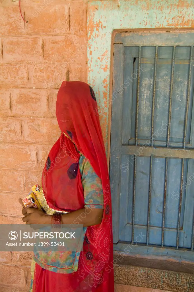 Portrait Of A Woman In Red Sari Against School Wall Near Jodhpur In Rajasthan India