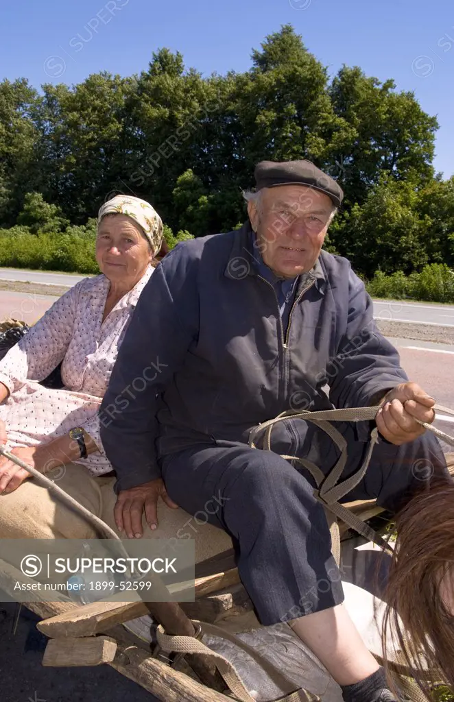 Farming Couple Riding On Horse-Drawn Cart On Road From Kiev To Lviv In The Ukraine