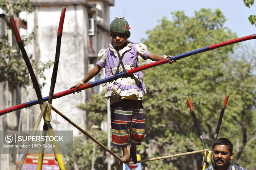 South Asian Girl Working Street Performer Balancing Act By Walking On Rope With Bamboo In Hand
