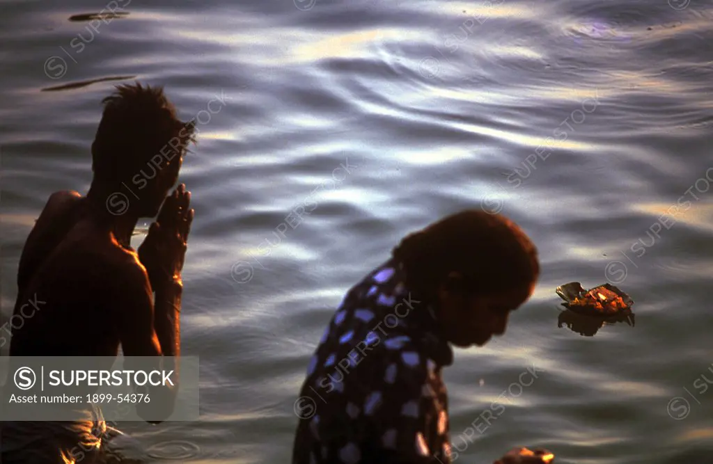 Man And Women Bathing Doing Namaskar Prayer To Sun Diya Oil Lamp Floating In The Holy River Ganges In The Oldest Indian City Of India, Banaras, Now Varanasi, Uttar Pradesh, India.