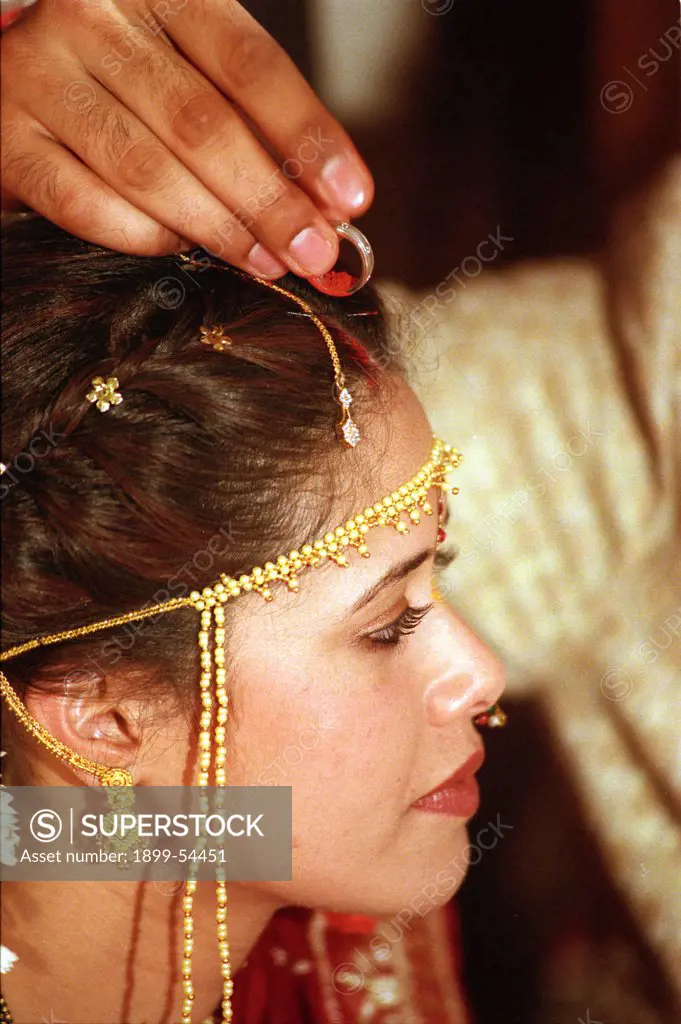 Indian Wedding Bride Dressed In Saree & Traditional Make Up Groom Filling His Bride With Kumkum Or Sindoor