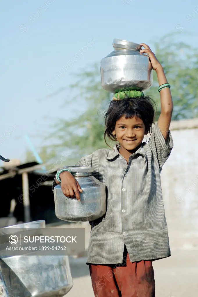 Young Boy Carrying Two Water Pots Made Of Steel In Anjar, Kutch, Gujarat, India