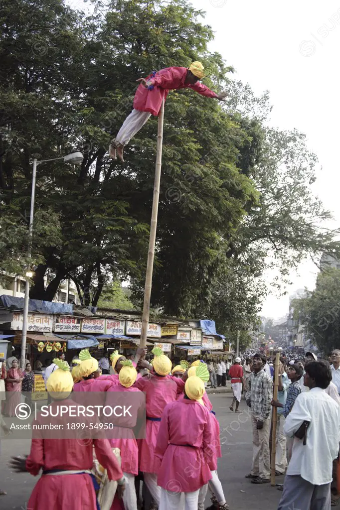 Adivasi From Mokhada Performing Acrobatics On The Beats Of The Drum During The Religious Procession At Court Naka, Thane, Maharashtra, India