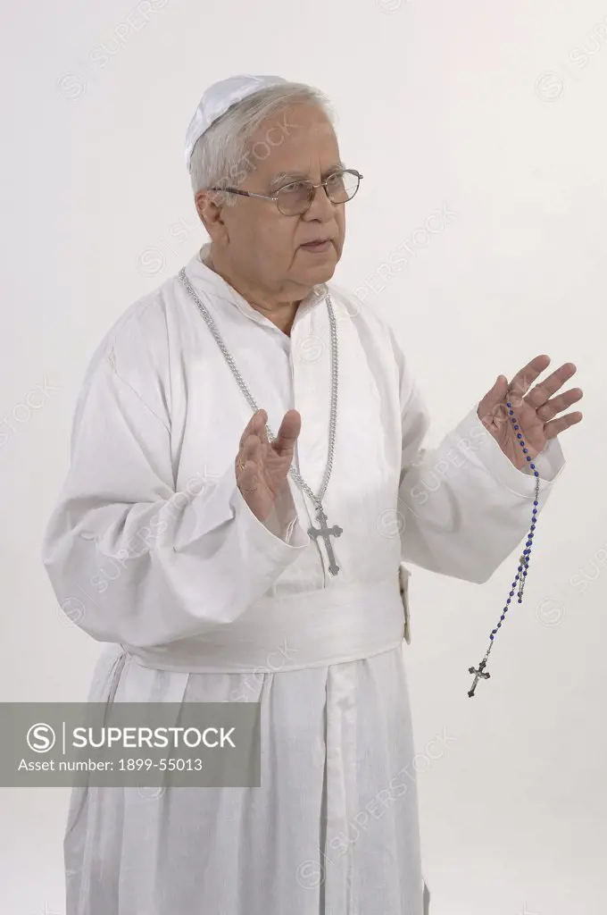Man Dressed In White Robe And Prayer Cap. Holding Rosary Beads