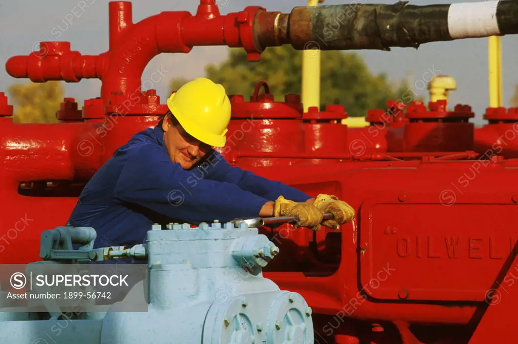 Man Making Adjustment On Drilling Rig For Oil Well