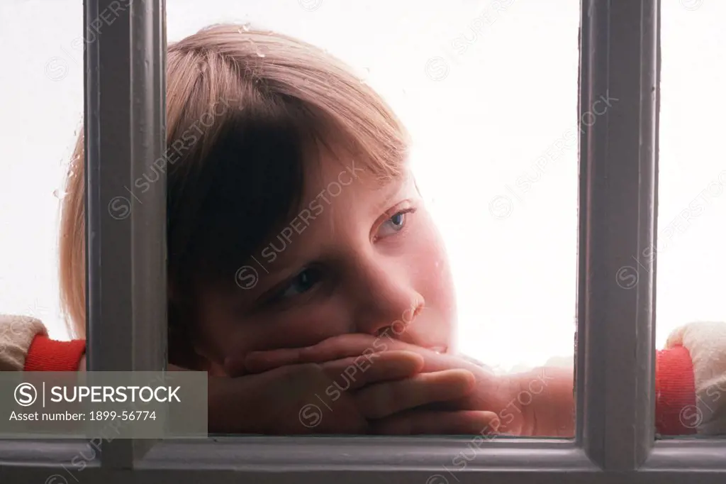 Lonely Child Standing At Her Window Looking Outdoors