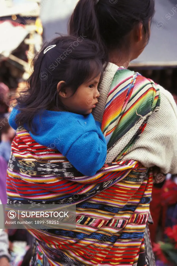 Guatemala, Chichicastenango. Woman Carrying Her Child On Her Back In Traditional Manner