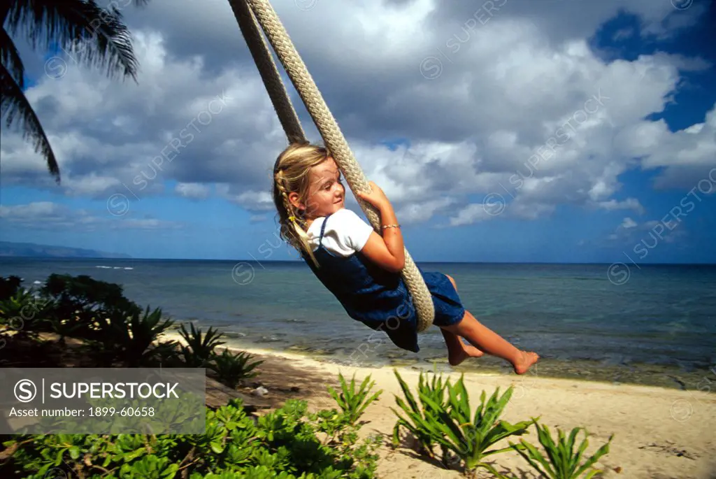 Girl (4) On A Rope Swing At Sunset Point On The North Shore Of Oahu, Hawaii.