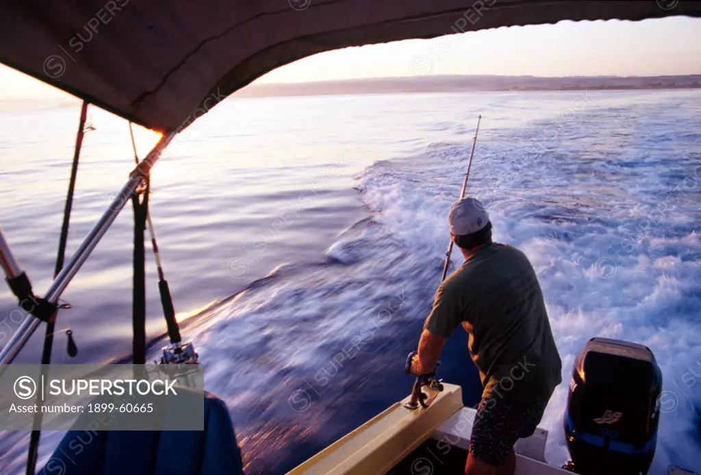 Man Rigging Deep Sea Fishing Poles On Fishing Boat Off The North Shore Of Oahu, Hawaii.