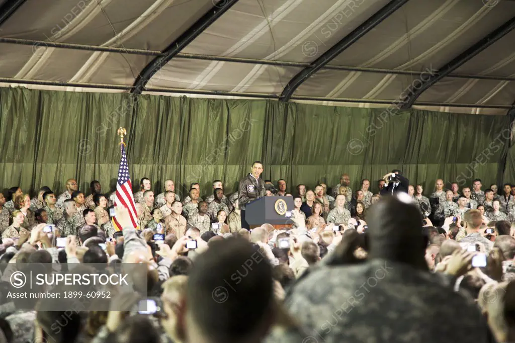 President Of The United States Barack Obama, Center, Delivers A Speech To A Crowd Of U.S. Soldiers, On Stage, Inside A Hanger, At Bagram Airfield, Afghanistan, Mar. 28, 2010.