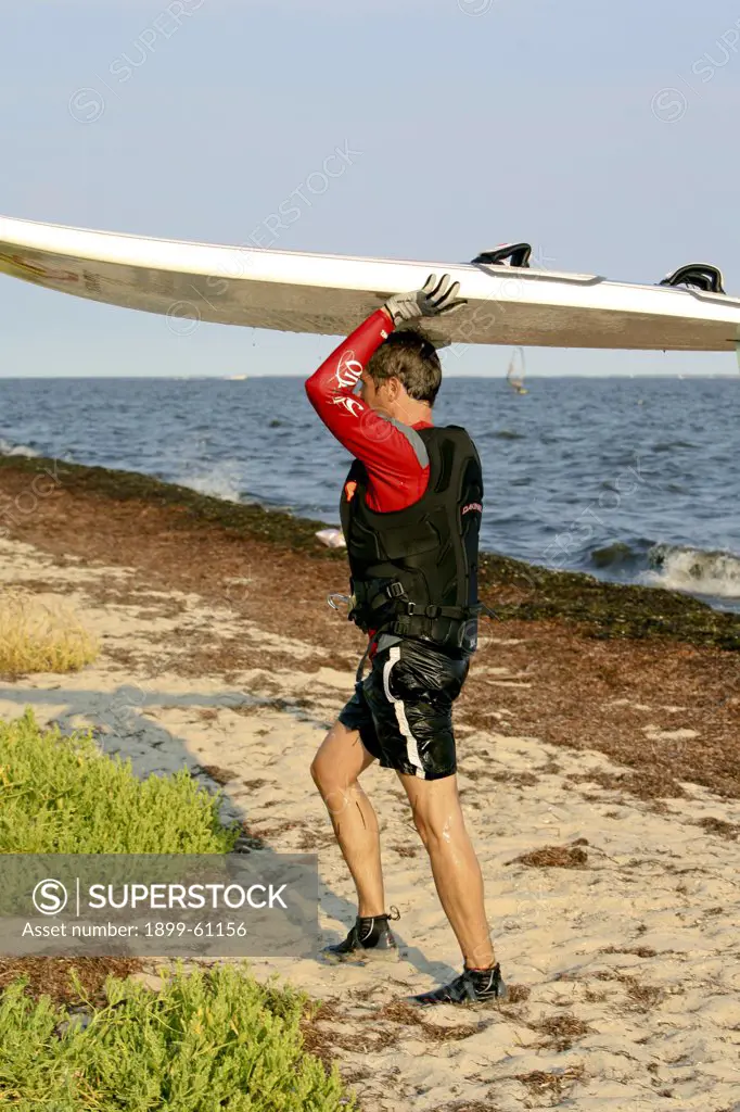 Man Carrying Windsurfing Board