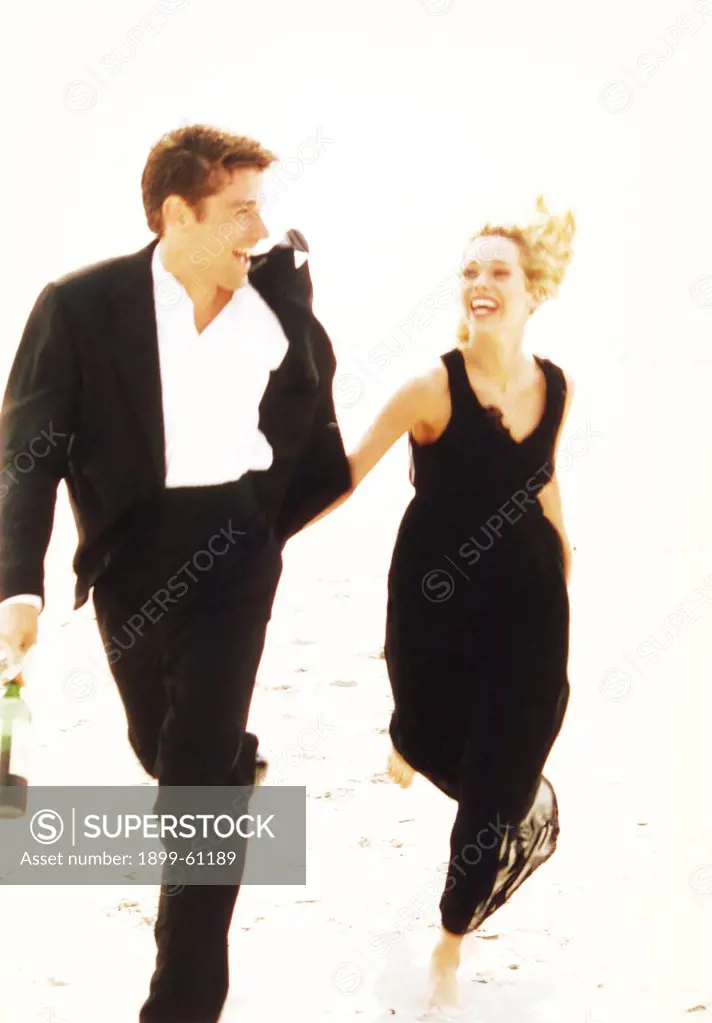 Man And Woman In Formal Attire Running On Beach.